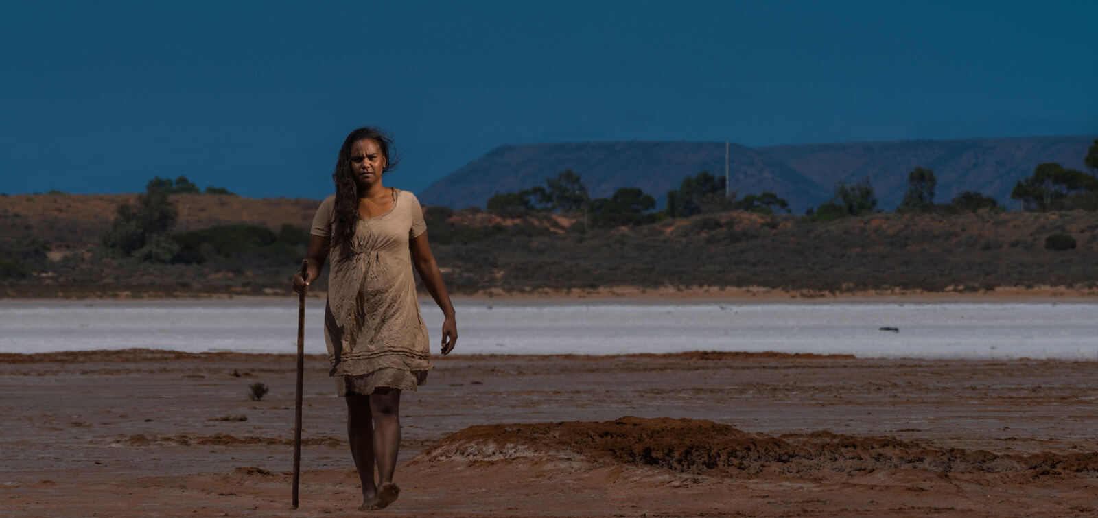 Wanita walking with a staff across the salt flats