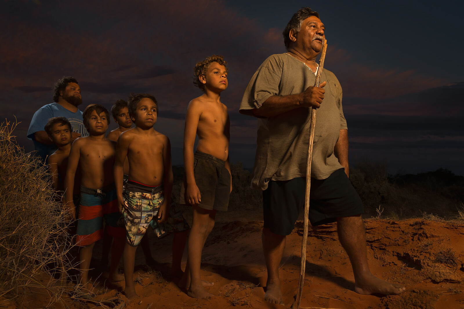 An Elder and boys standing together on the sand hills