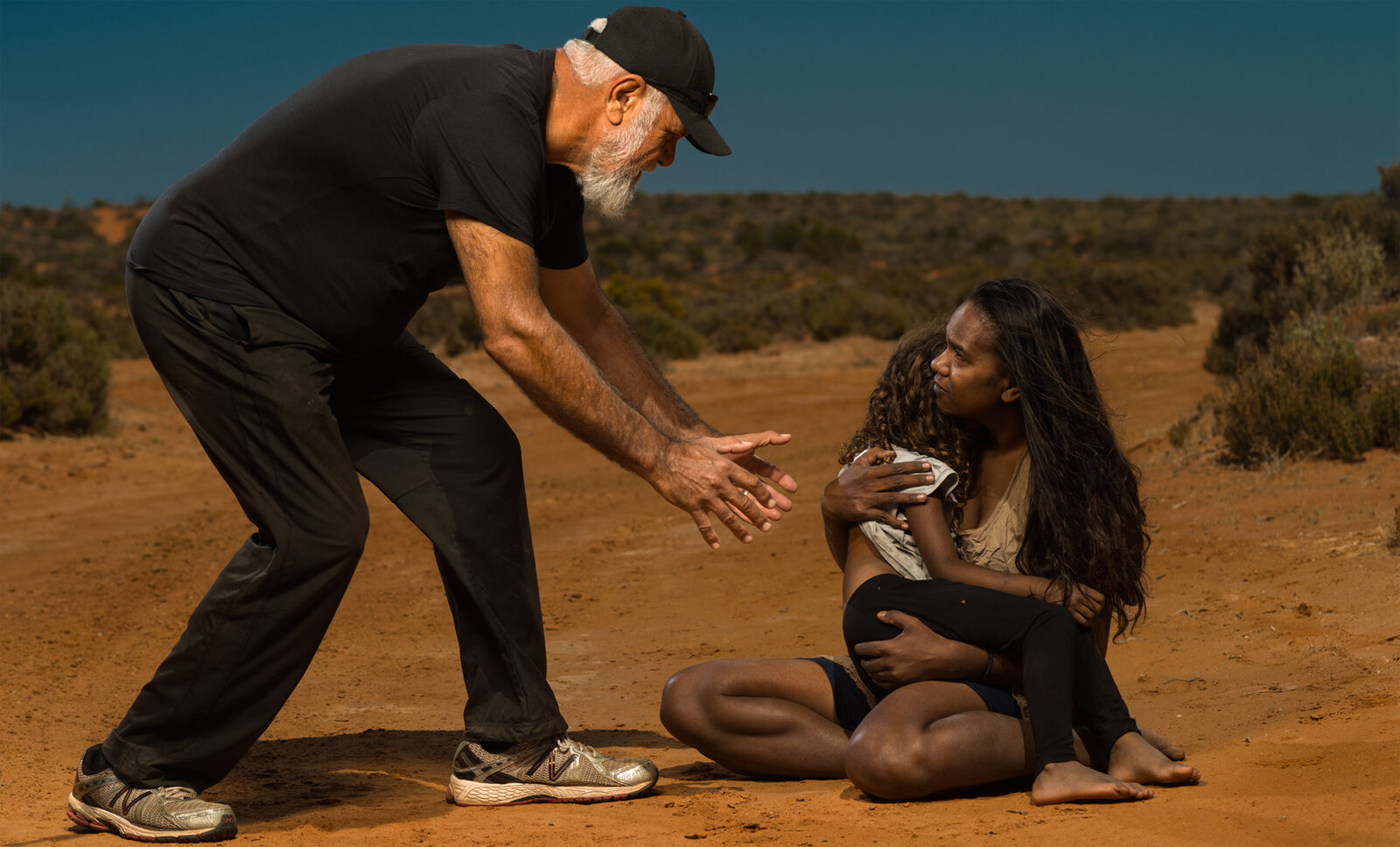 Uncle Paul Tanner reaching toward a mother holding a child