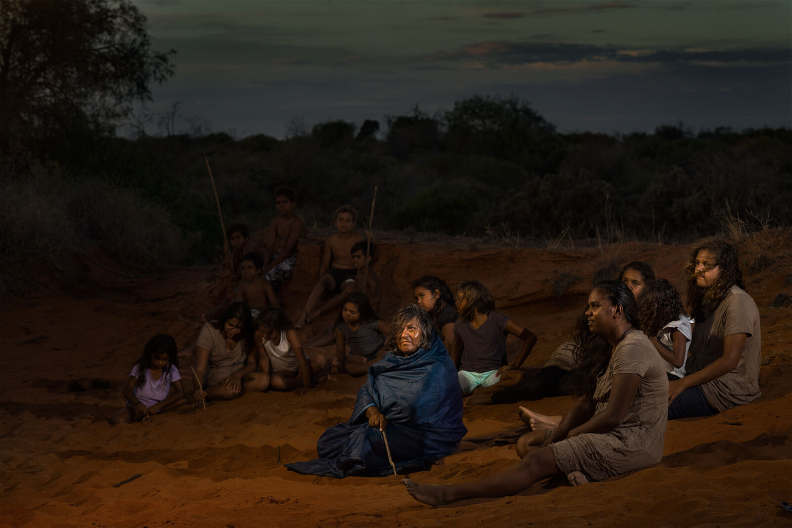 The Mob gathered with an Elder on the red sand at dusk