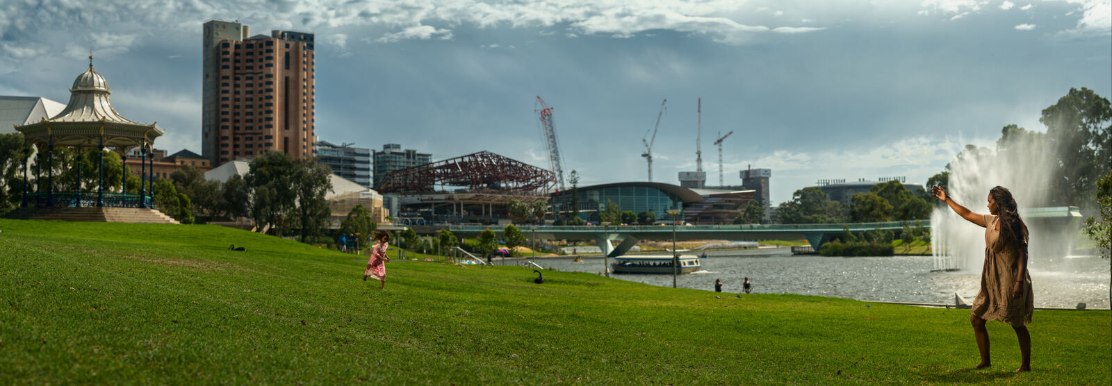A child running across Elder Park toward her mother